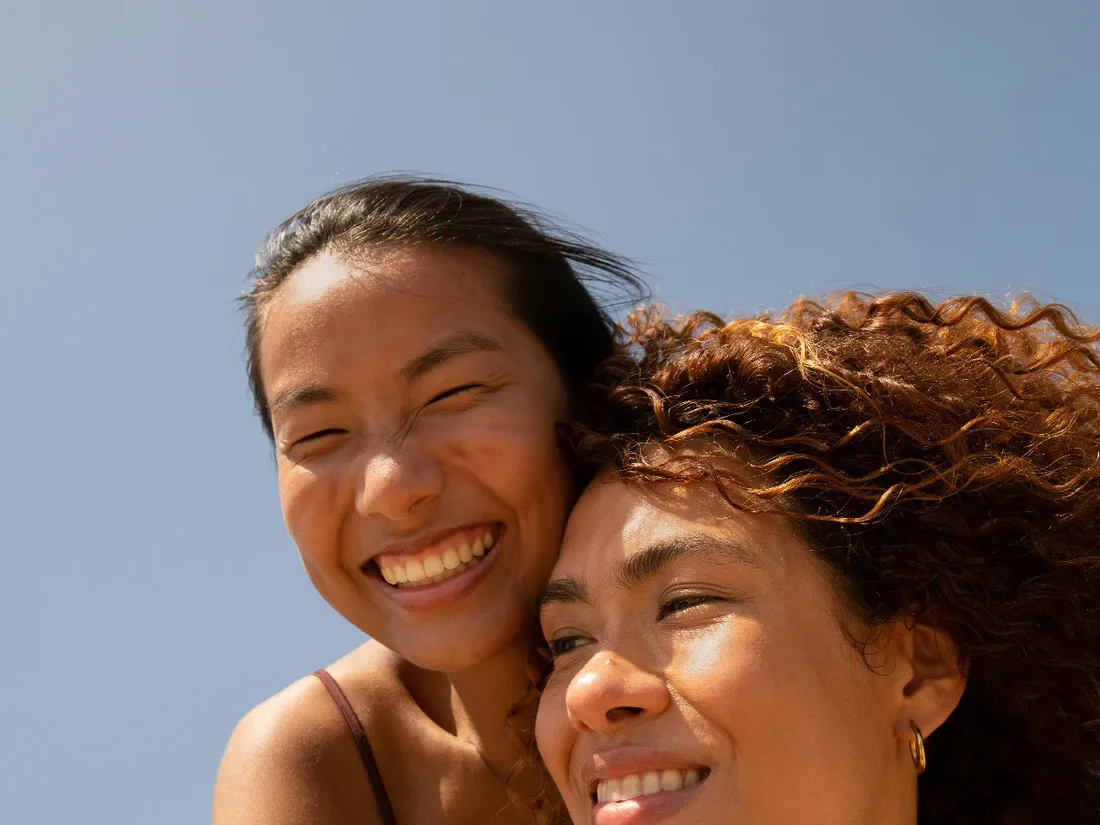 Two women outdoors in bright daylight, relaxed and laughing together