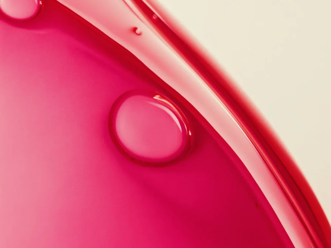 A close, clinical study of deep red serum against a pale background